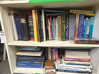 Two shelves filled with assorted hardcover and softcover books, visible titles include nautical, dictionaries and history