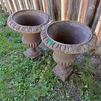 Pair of matching cast concrete urns on grass