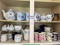 Full cabinet view showing teapots, mugs, pitchers, sugar bowls and creamer