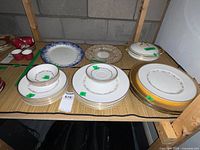 Overall lot on shelf showing stacks of plates, bowls, saucers, chargers and serving pieces