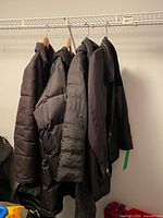 Four black jackets hanging on rack