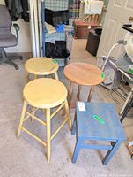 Group shot of two yellow stools, round side table, blue stool