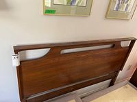 Front view of wooden headboard mounted on wall beneath framed art