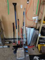 Group view of long-handled tools, pump, sunshades and smaller items on floor