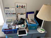 Overview of lot showing lamp, electronics, books and baskets