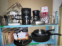Overall view of shelf showing all appliances, cookware, slow cooker box, cookbooks