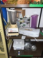 Shelf view showing blender, vacuum sealer, chopper box, pitcher, Brita dispenser, metal canisters