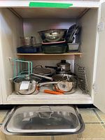 Cabinet view showing saucepans, racks, lids, roasting pan lid