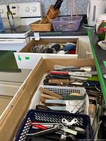 Open drawers and baskets showing variety of utensils and flatware