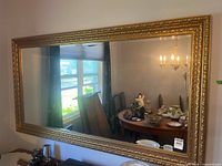 Front view of large gold ornate framed mirror mounted on wall