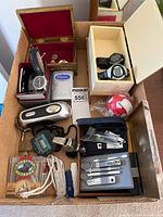 Overview of entire lot inside box showing Timex watch, digital watches, Sony Walkman, pocket knives, grooming sets and other items
