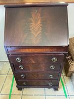 Front view showing closed drop-front, four drawers, brass hardware, overall appearance