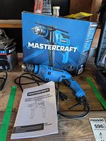 Hammer drill, power cord, box and manual on workbench