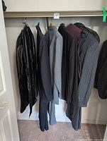Multiple hanging suits and garments in closet