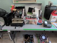 Overview of table with shredder, calculators, laminator, organizers, cables and writing instruments