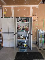 Tall grey plastic storage cabinet, doors open showing adjustable shelves, measuring approx 30x70x16 in