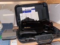 Camcorder inside case with Polaroid unit, manual visible