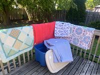 Overview of all comforters draped on railing and storage bin
