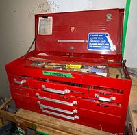 Front view of red metal tool chest, lid open showing drawers