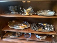 Cabinet shelves showing punch bowl, gravy boat, glass divided dish, oval tray with carving utensils, flatware stacks, serving utensils