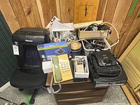 Overall view of lot on cabinet showing electronics, phone, bins, clock, chair