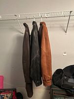 Three leather jackets hanging side by side on wire shelf
