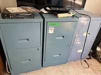 Front view of three metal two-drawer filing cabinets placed side by side under electronics