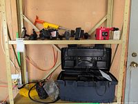 Shelf with red air compressor, yellow hose, suction mounts, open black toolbox