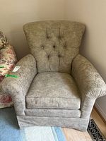 Front view of tufted beige armchair showing overall design and stains