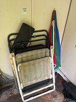 Stacked view of both chairs folded with umbrella leaning against wall