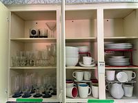Cabinet view showing entire assortment of dinnerware, glassware and racks