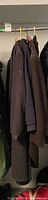 Three garments hanging: navy sweater, charcoal coat, brown coat
