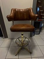 Front view of stool showing upholstery, arms, brass base