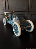 Left front three-quarter view of blue porcelain 1906 Renault race car decanter showing wheels, cockpit and stopper