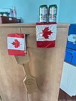 Overall lot showing paddle hanging and two small Canadian flags mounted in metal double flag holder