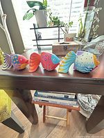 Front view of three multicolor wooden fish figurines on table