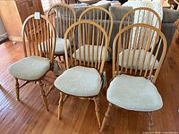 Front view of six matching spindle-back wood chairs with cushions