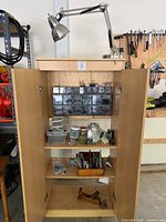 Full view of open cabinet showing lamp, drawer organizers, shelves and contents