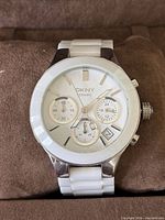Front view of DKNY white ceramic chronograph watch on pillow