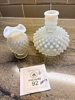 Both opalescent hobnail vases with lot tag visible