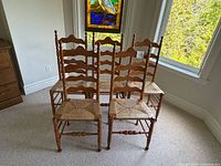 five wooden ladder-back chairs front view