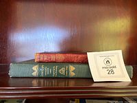 Two books stacked: red Oliver Twist on top, green Jane Eyre beneath