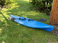 Full view of blue Wilderness Systems Critter kayak with paddle on grass