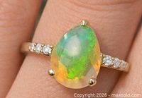 Ring on finger showcasing pear opal and diamond shoulder accents