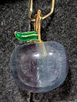 Front view of carved fluorite apple pendant showing gold-tone stem, green enamel leaf and bail