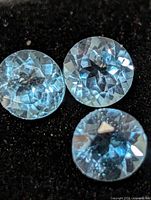 Close-up of three round blue topaz stones showing facet pattern and color