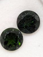 Close-up of two round green chrome diopsides showing faceting and colour