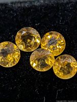Close-up of five round yellow gemstones on black background