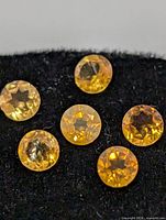 Close-up of six round yellow gemstones on black backing