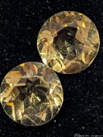 Two round golden citrines on black background